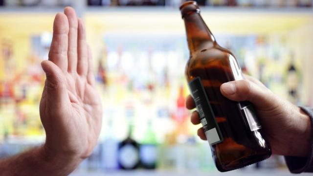 Una mano parando una botella de alcohol