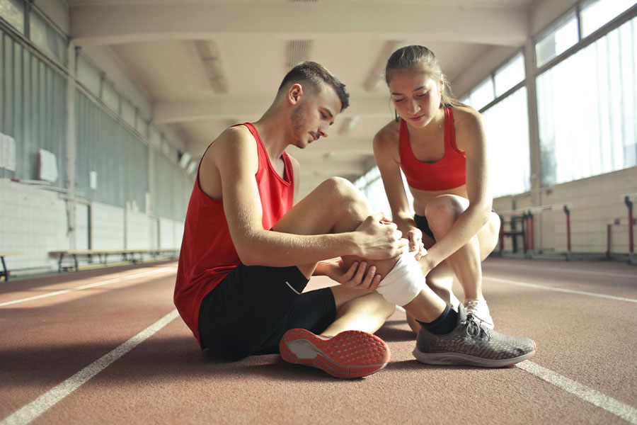 Chica ayudando a un deportista en su lesión